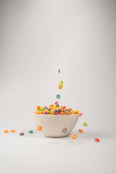 Colorful cereal box for morning breakfast. Corn flakes falling to the white bowl. Motion. Copyspace. - Foto, Imagem