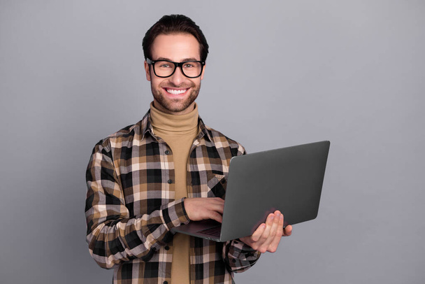 Photo of charming cheerful man wear plaid shirt spectacles working modern gadget isolated grey color background - Foto, imagen
