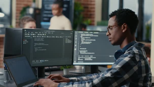 ソフトウェア開発者は、複数の画面で机の上に座ってノートパソコンを入力しながらひげに触れながら考える - 映像、動画