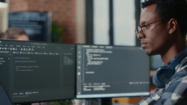 Portrait of focused software developer writing code arranging glasses sitting at desk - Filmati, video
