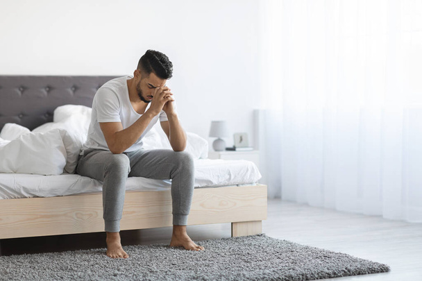 Despair Concept. Portrait Of Depressed Arab Man Sitting On Bed At Home - Foto, Imagem
