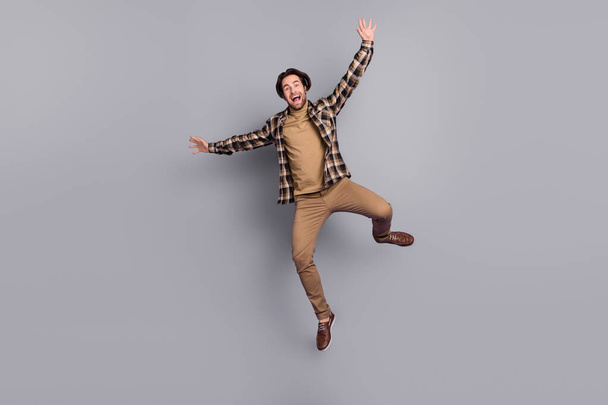 Photo of funny charming man wear plaid shirt jumping high like star isolated grey color background - Photo, Image