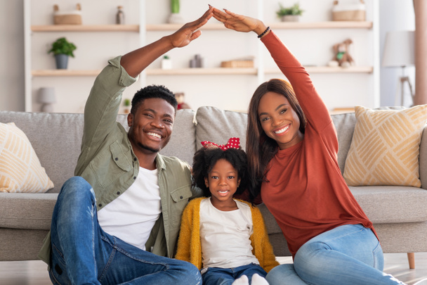 Family Housing. Black Parents Making Symbolic Roof Of Hands Above Little Daughter - Valokuva, kuva