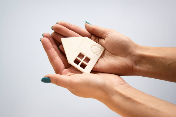 Hands holding white paper house, family home, homeless housing and home protection insurance concept, international day of families, foster home care, family day care, social distancing. - Photo, Image