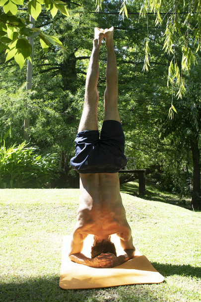 йога на відкритому повітрі в розслабленому положенні, молодий і гнучкий чоловік, з помаранчевим йога килимом
 - Фото, зображення