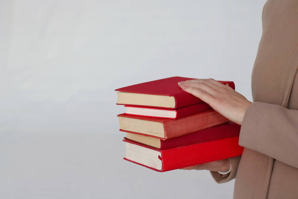 Ένα νεαρό όμορφο κορίτσι που κρατάει βιβλία στα χέρια της. - Φωτογραφία, εικόνα