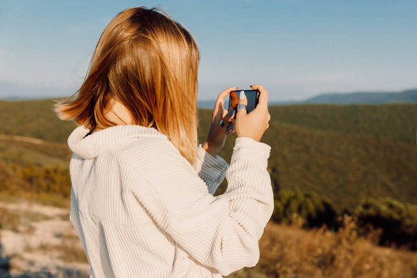 Blonde woman outdoor photography with smartphone. Girl shooting landscapes on smartphone - Photo, image
