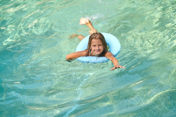 Sweet little girl swimming on a tube and smiling - Foto, immagini