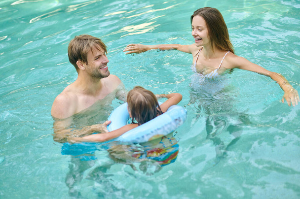 Parents teaching theri daughter to swim and looking involved - 写真・画像