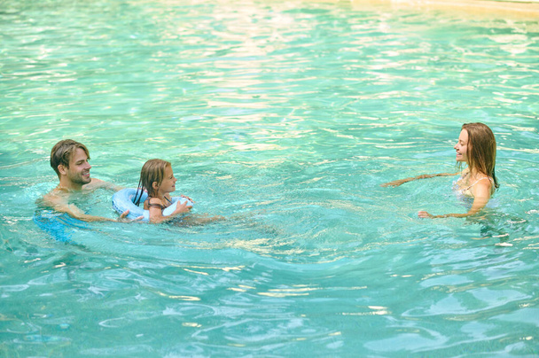 Parents teaching theri daughter to swim and looking involved - Foto, Imagen