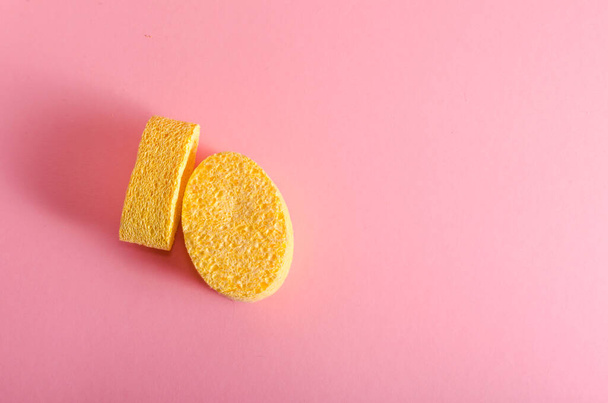 yellow sponge for washing the face on a pink background. Copy space for text. High quality photo - Valokuva, kuva