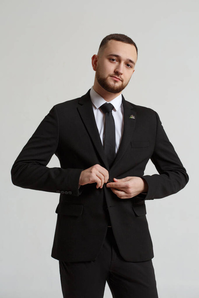 Young man with a beard in a business suit isolated on a gray background. - Fotografie, Obrázek