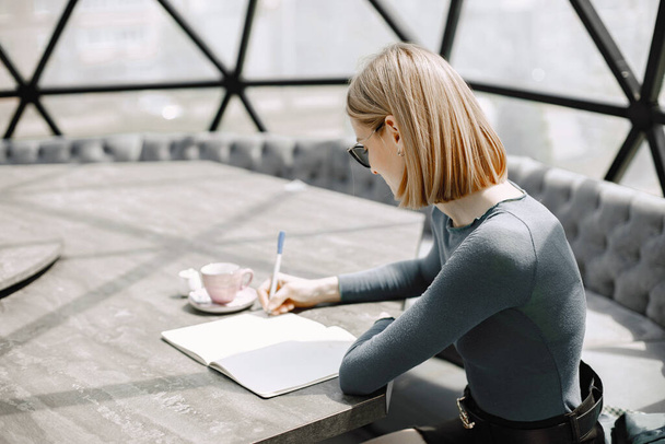 Portrait of businesswoman writes on a document while sitting in a cafe - Photo, image