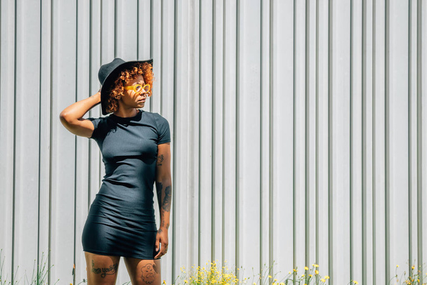 Afro-Amerikan şehirli, modaya uygun şapkalı, fotokopi için duvarları olan bir kız. - Fotoğraf, Görsel