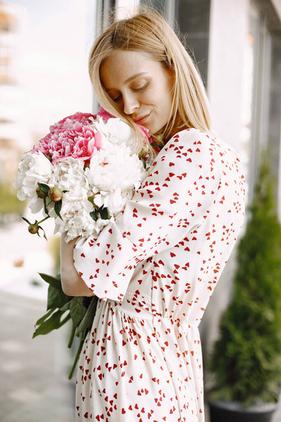 Young blonde woman standing near cafe and holding a bouquet of flowers - Foto, Imagem