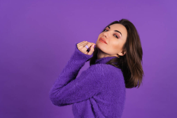 Young woman in a purple soft cozy sweater on the background of cute smiling cheerfully, in high spirits, confident smile, bright makeup with lipstick - Zdjęcie, obraz
