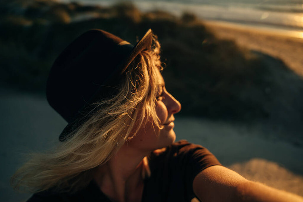 selfie of a traveler on the beach wearing a hat at sunset. High quality photo - Fotoğraf, Görsel