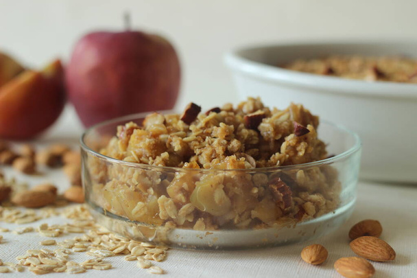 Apple crisp. Cinnamon flavoured apple dessert with lots of chopped apples arranged in a bake dish topped with a mixture of rolled oats, wheat flour, nuts, butter, brown sugar, cinnamon - Photo, Image