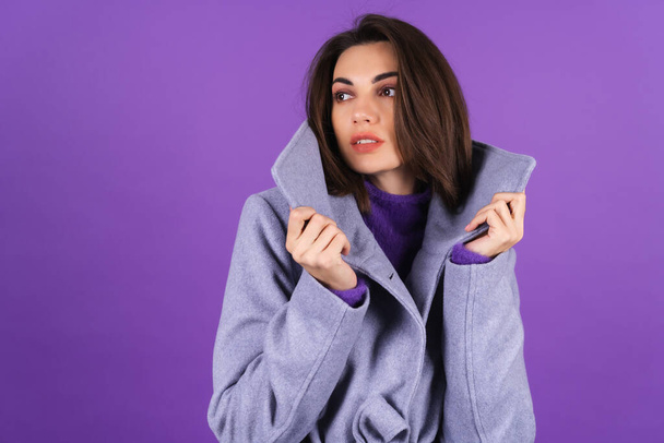 Young woman in a gray coat on a purple background posing, cozy and warm, autumn winter style - Φωτογραφία, εικόνα
