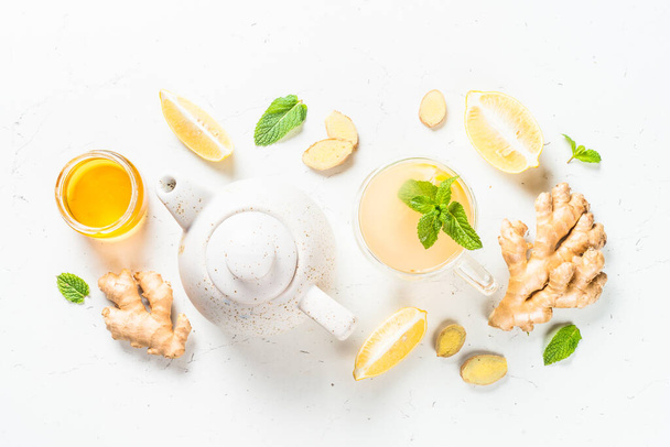 Имбирный чай с лимоном за белым столом. - Фото, изображение