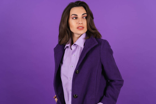 Young woman in a woolen coat on a purple background posing, cozy and warm, autumn-winter style - Foto, afbeelding