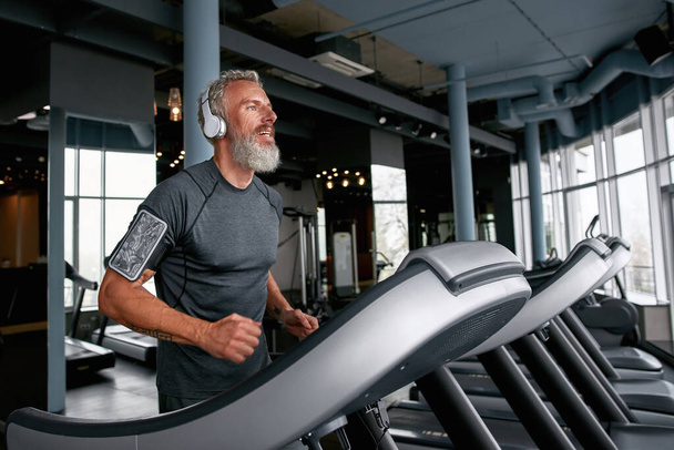 Aged man on treadmill, running over the top - Fotó, kép