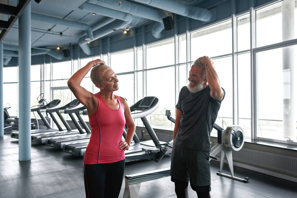 Cheerful aged people stretching neck in health club - Photo, image