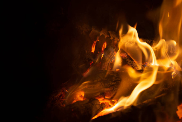 Burning wood in a campfire close-up. Selective focus. Charcoal in a bright red flame. Flashes and sparks in the fire of a forest fire. The concept of warmth and comfort. - Foto, Imagen
