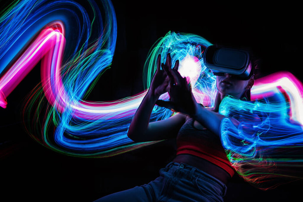 Metaverse digital Avatar, Metaverse Presence, digital technology, cyber world, virtual reality, futuristic lifestyle. Woman in VR glasses playing AR augmented reality NFT game with neon blur lines - Fotografie, Obrázek