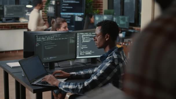 Фокусований програміст фіксує окуляри під час друку на ноутбуці, сидячи за столом з декількома екранами
 - Кадри, відео