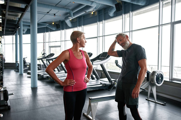 Portrait of elderly lady standing next to her handsome husband in gym - Photo, image