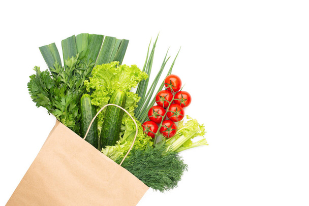 Un conjunto de verduras y hierbas en una bolsa de papel aislada sobre fondo blanco. Concepto: Compras en un supermercado o mercado y comida vegetariana saludable. - Foto, Imagen