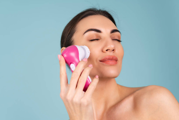 Close-up beauty portrait of topless woman with perfect skin and natural makeup, full nude lips, holding an electric facial brush. Facial cleansing with microvibrations - Φωτογραφία, εικόνα