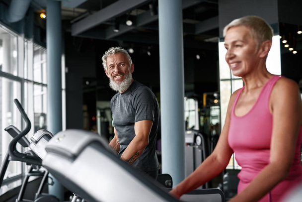 Seniors workout in gym. Smiling man looking at woman - Foto, Imagem