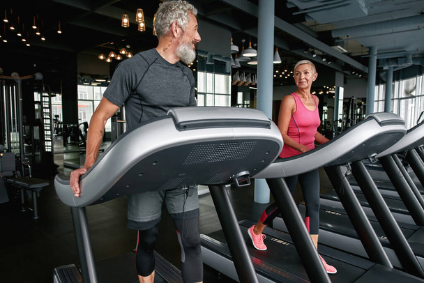 Handsome aged man flirting with lovely middle-aged woman in gym - Photo, Image
