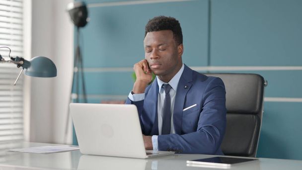 Fáradt afrikai üzletember szundikál, miközben ül az irodában Laptop - Fotó, kép