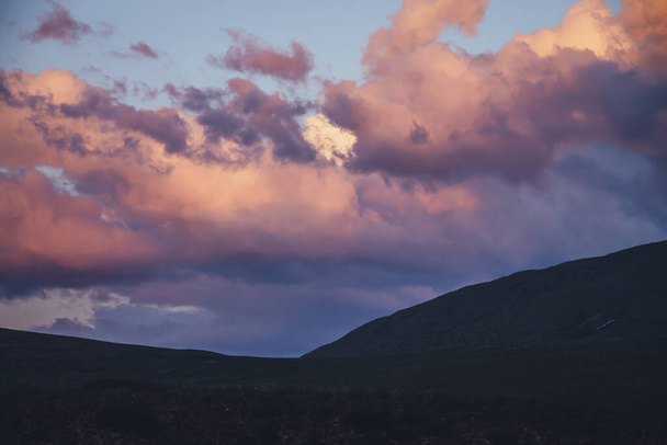 Escenario de montaña mínimo atmosférico con cielo de amanecer lila. Paisaje minimalista escénico con puesta de sol púrpura en las montañas. Hermoso amanecer en las montañas en tonos pastel. Montaña rocosa en el cielo nublado del amanecer - Foto, imagen
