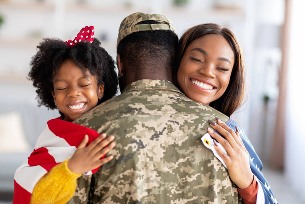 Αντίληψη επιστροφής. Αμερικανός στρατιώτης Αγκαλιάζοντας τη σύζυγο και την κόρη μετά την επιστροφή από το στρατό - Φωτογραφία, εικόνα