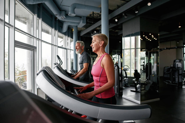 Senior woman and man feeling happy, exercising in gym - Photo, image