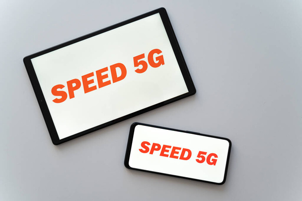 Teléfono y tablet, con texto "speed 5g" en rojo, en la pantalla. Nuevo estándar de transmisión de datos 5g.  - Foto, Imagen