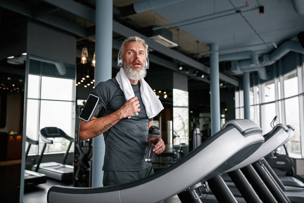 Exhausted mature man after working out in sports center - Photo, Image