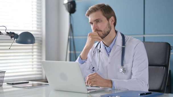 Lekarz myślenie podczas pracy na laptopie w klinice - Zdjęcie, obraz