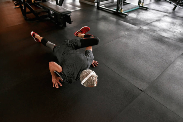 Faceless man on floor doing planks at gym - 写真・画像