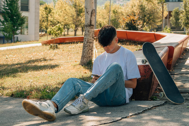 teenage boy with mobile phone and skateboard on the street - Zdjęcie, obraz