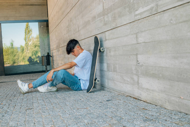 adolescent avec téléphone portable et planche à roulettes dans la rue - Photo, image