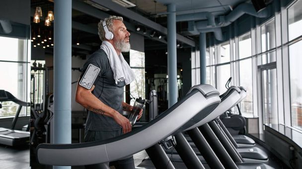 Tired man finished cardio exercises on treadmill - Fotó, kép