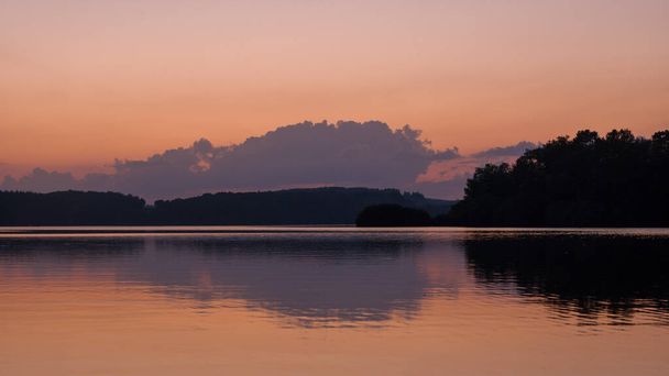 Cette photo de paysage a été prise en Europe, France, Bourgogne, Nièvre, Morvan, en été. On peut voir les reflets des arbres sur le lac des Settons au coucher du soleil. - Photo, image