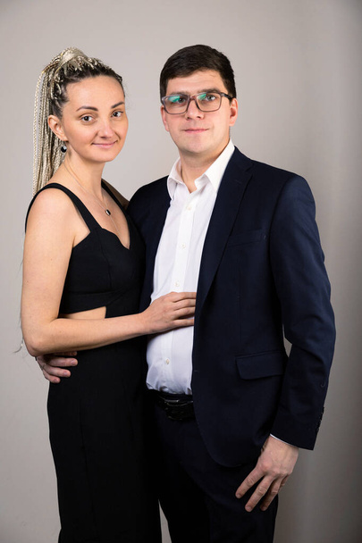 the couple looks into the camera against the background of a gray wall - Foto, Imagen