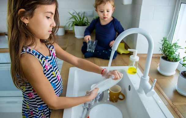 Kinderen wassen de afwas in de keuken. Selectieve focus. Jongen. - Foto, afbeelding