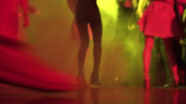 Vista de cerca de las piernas de la gente bailando en el club nocturno entre el humo y el espectáculo de luz - Metraje, vídeo
